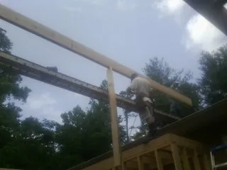 Carpenter setting a ridge beam over a new addition frame — Ice Dam Removal by Roofing Brothers in Fiskdale