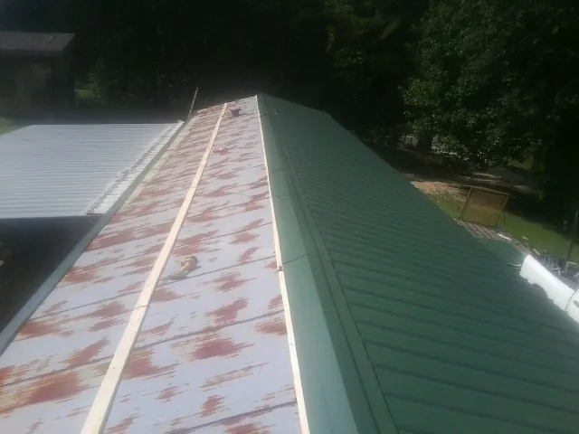 Old rusted panels beside newly installed green metal roofing — Wind Damage Roof Repair by Roofing Brothers in Fiskdale