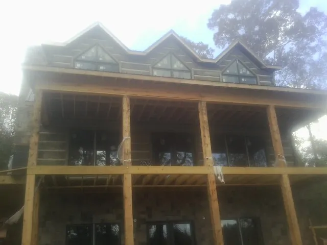 Dormers and porch framing on a large log home under construction — Roof Coating work by our crew in Fiskdale