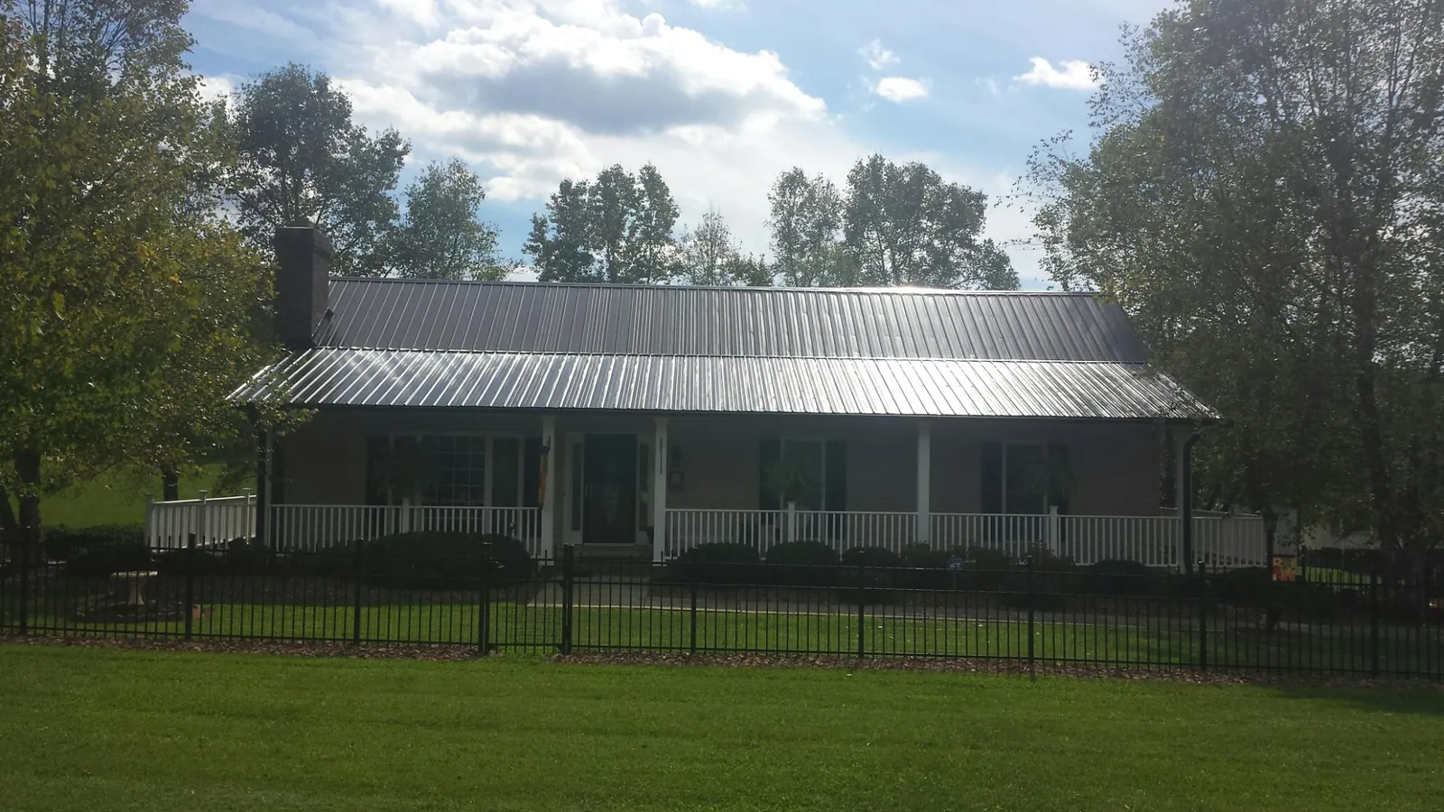 Gray metal roof on a brick ranch with a full width front porch — Gutter Guard Installation work by our crew in Fiskdale