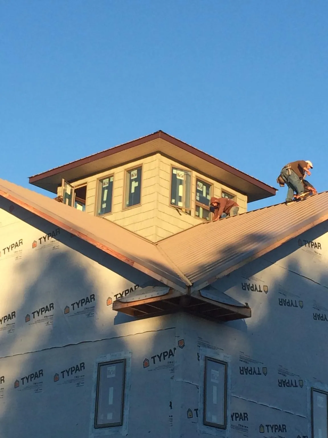 Roofers working around a rooftop cupola on a new metal roof at sunset — Roof Waterproofing in Fiskdale by Roofing Brothers